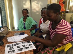 The beneficiary signs the contract for the purchase of the bicycle, observed by her two moral guarantors